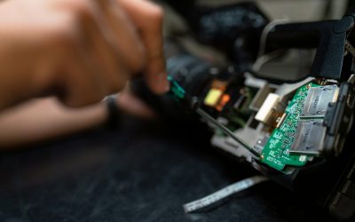 A person using a screwdriver to repair or assemble an electronic device with visible circuit boards and components.